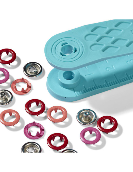 Doos met 21 drukknopen in rood, koraal en fuchsia met 8 mm gereedschap.